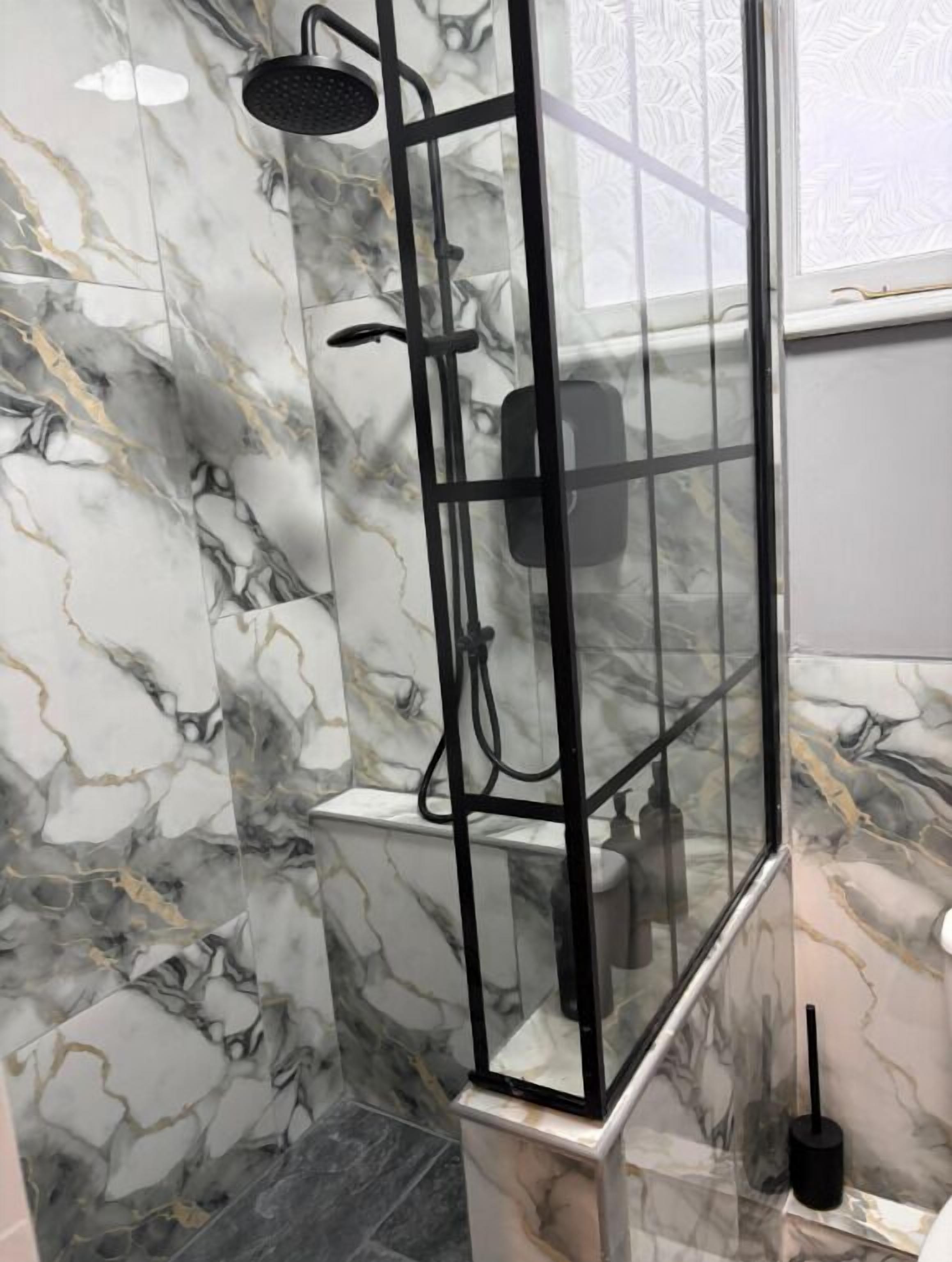A shower enclosure with a glass door and a handheld showerhead.