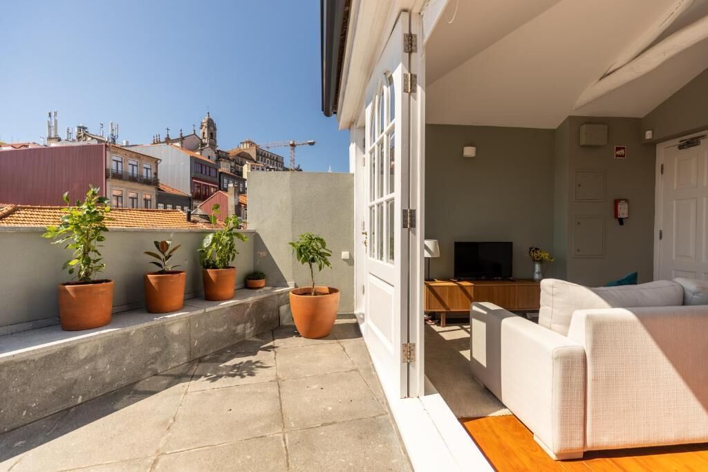 A balcony with potted plants, a white sofa, and a TV.