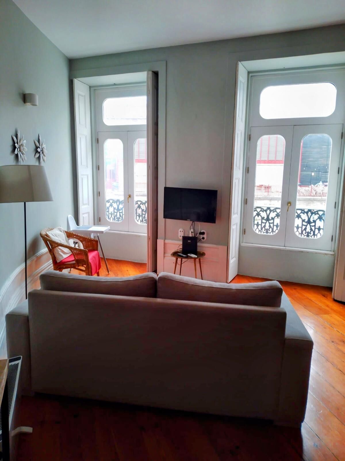 A living room with a sofa, a TV on a stand, a lamp, and a window with a view.