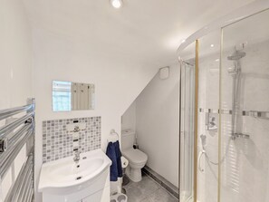 Un baño moderno con ducha acristalada, lavabo blanco y retrete.