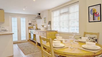 Een koelkast, een broodrooster, kookgerei, borden en bestek, eettafels