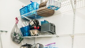 Keittiössä on hyllyjä, joilla säilytetään erilaisia keittiötarvikkeita, mikroaaltouuni ja pölynimuri.
