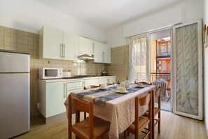 A compact kitchen with a dining table, chairs, and a view of the balcony. - Apartment 'Villa Trentina Trilocale 2 Piano' with Shared Terrace and Wi-Fi (Jesolo)
