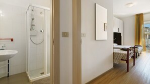 A hotel room with a shower, a bed, a bedside table, and a view of the outside. - Apartment 'Villa Trentina Trilocale 2 Piano' with Shared Terrace and Wi-Fi (Jesolo)
