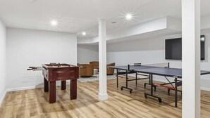 Une pièce équipée d’un baby-foot, d’une table de ping-pong et d’un téléviseur fixé au mur.