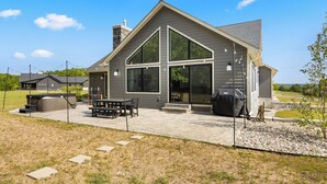 Une maison moderne dotée d’un grand patio, d’un espace barbecue et d’un coin salon extérieur abrité.