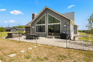 Een modern huis met een ruime patio, een barbecueplek en een overdekte zithoek buiten.
