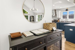 A kitchen with a dark wooden cabinet, a woven basket, and a mirror on the wall. - Innsbruck Chalet | Family-Friendly | Game Room | Fire Pit | Hot Tub (Boyne City)