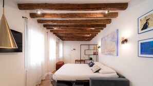 Un dormitorio con techo de madera, una cama, un escritorio y una silla.