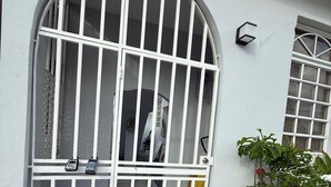 Un bâtiment blanc doté d’une grande entrée en arc de cercle, d’une terrasse carrelée et d’un pot de fleurs placé à côté de l’entrée.