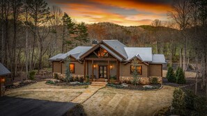 A two-story log cabin with a stone foundation, a front porch, and a driveway leading to the entrance. - Luxe Retreat at Blue Ridge - Pool | Hot Tub | Outdoor Kitchen | Firepit | Game Room (Epworth)