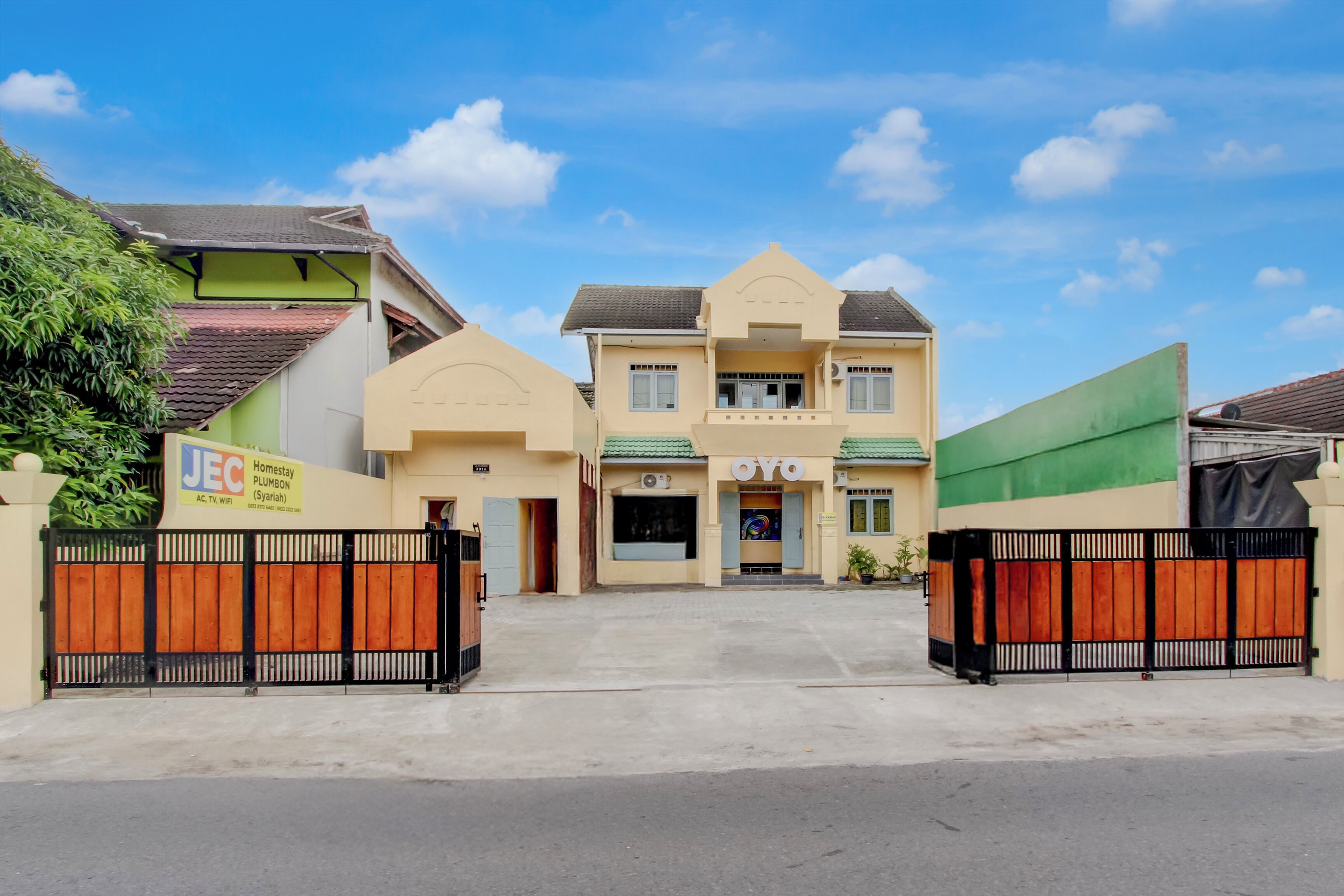 A two-story building with a green roof, a sign for 'JEC Plumbing,' and a 'Oyo' sign on the front.