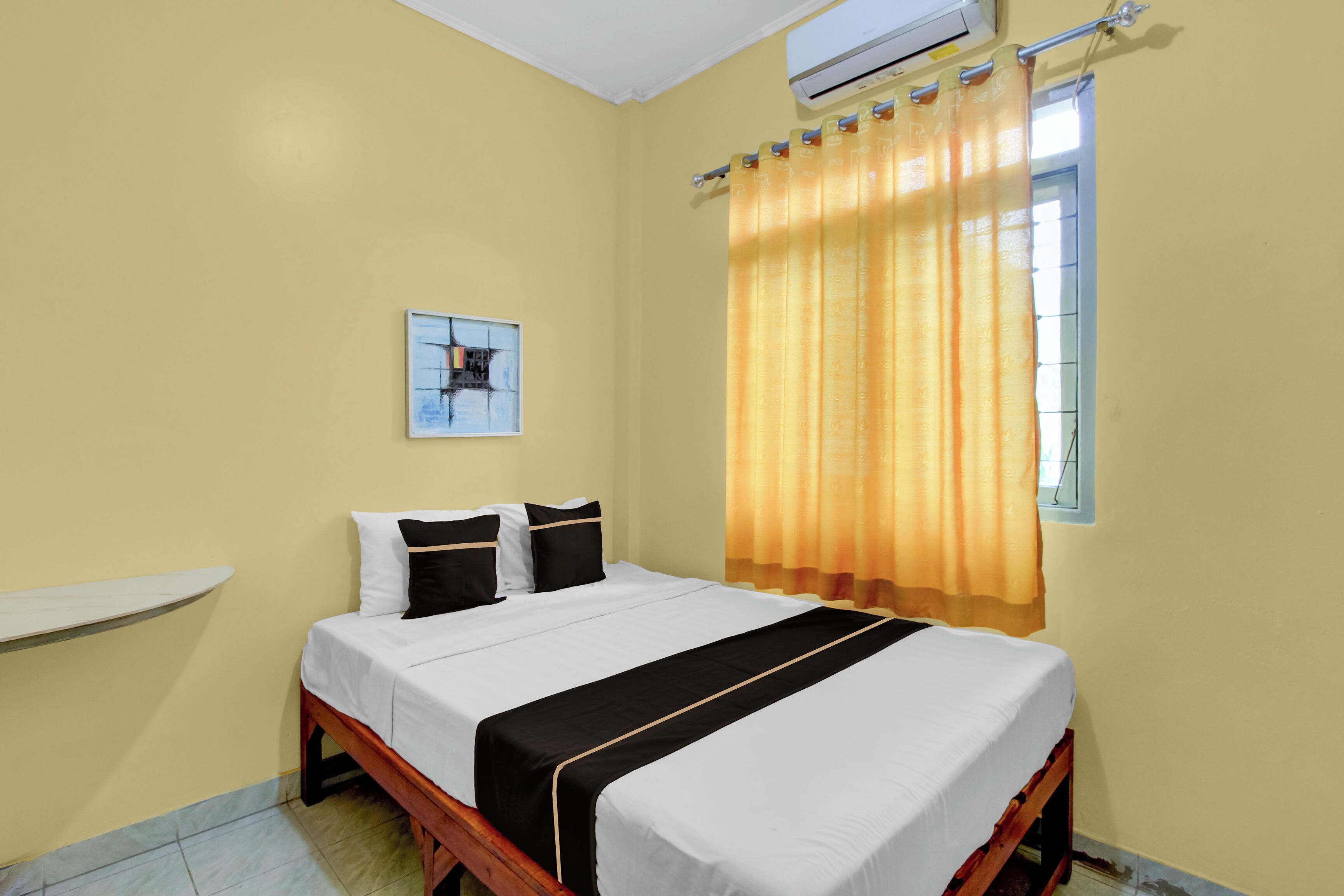 Un dormitorio con cama, ventana con cortinas, aire acondicionado de pared y repisa.