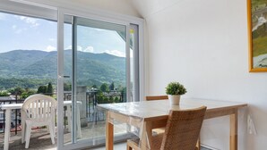 Un balcón con mesa y sillas, una planta en maceta y vistas a montañas.