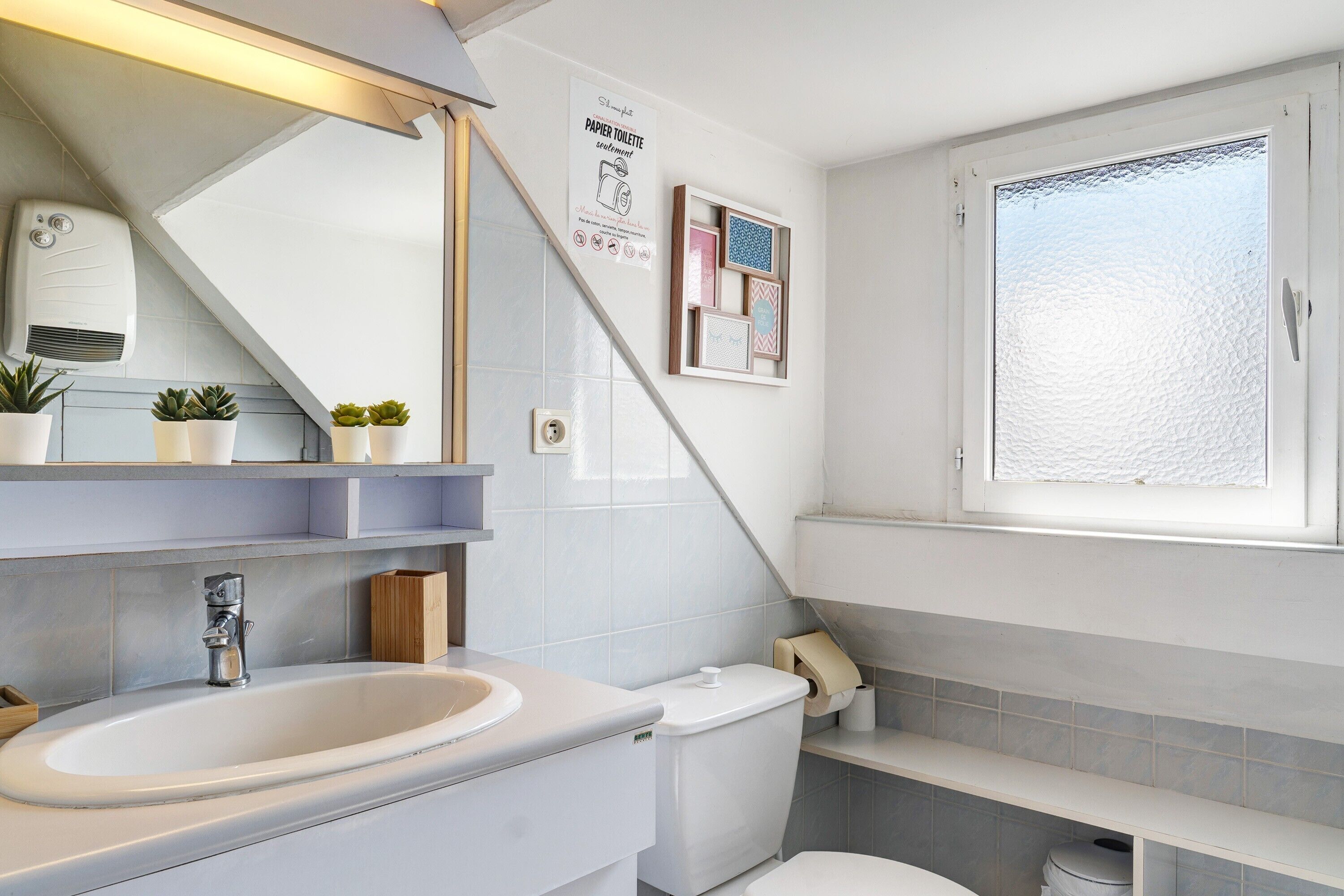 Un baño con lavamanos, inodoro y ventana.
