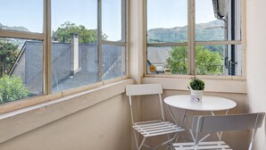 Una habitación con un ventanal grande, una mesita y una silla.