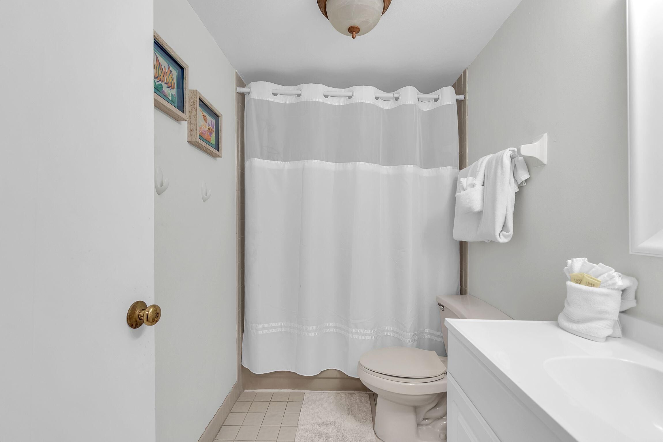 Ein Badezimmer mit Toilette, Waschbecken, Duschvorhang und Handtuchhalter.