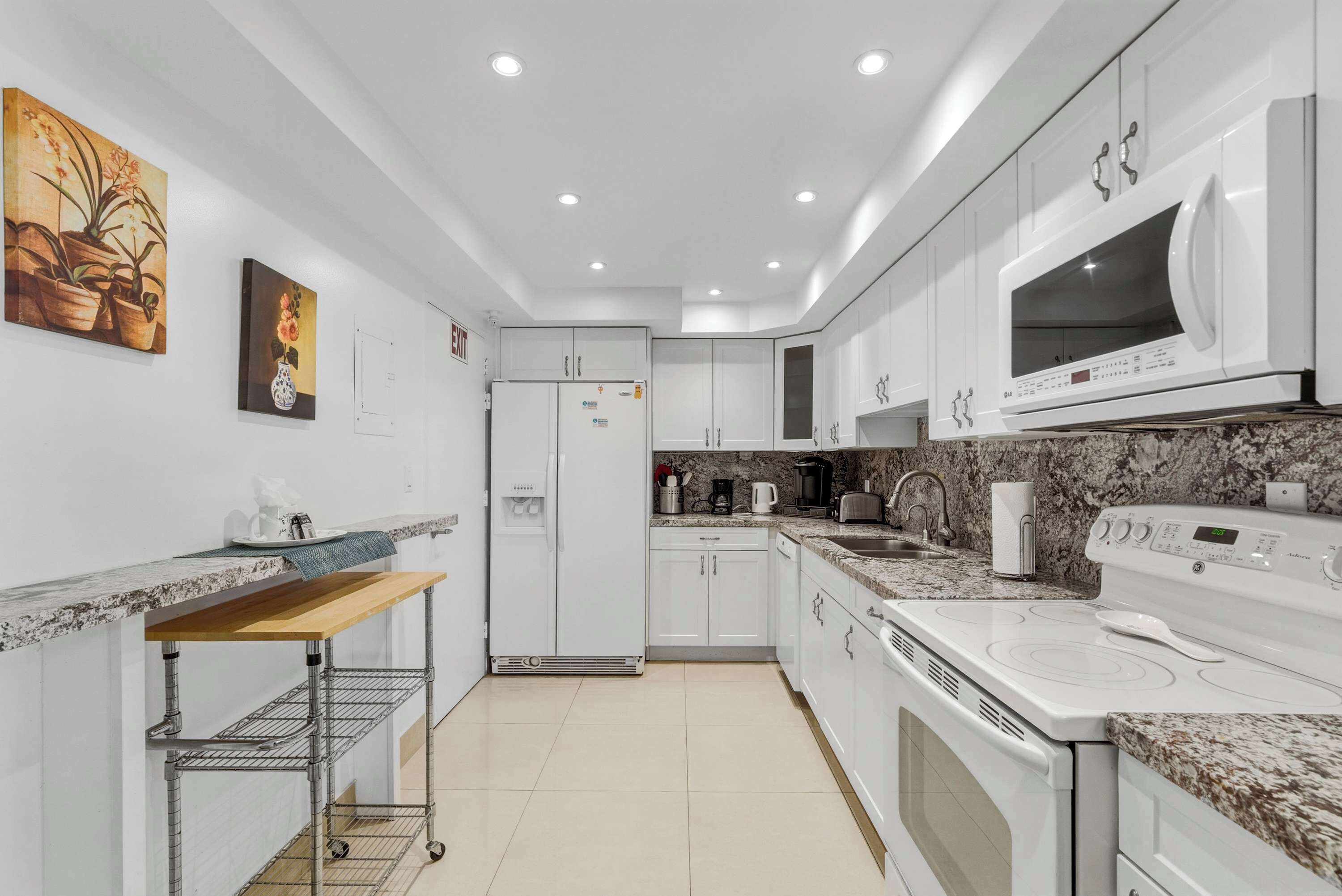 A modern kitchen with white cabinets, a microwave, a stove, and a refrigerator.
