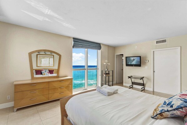 A bedroom with a large bed, a dresser, a television, and a view of the ocean. - Tides Building Beachfront - Ocean Views - We Host (Hollywood)