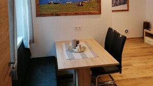 A dining area with a wooden table, black chairs, a bench, and a hanging light fixture.