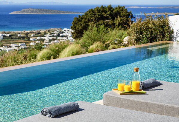 A poolside area with a clear view of the sea and a distant island. - Paros Villa Skylines Estate II (Paros)