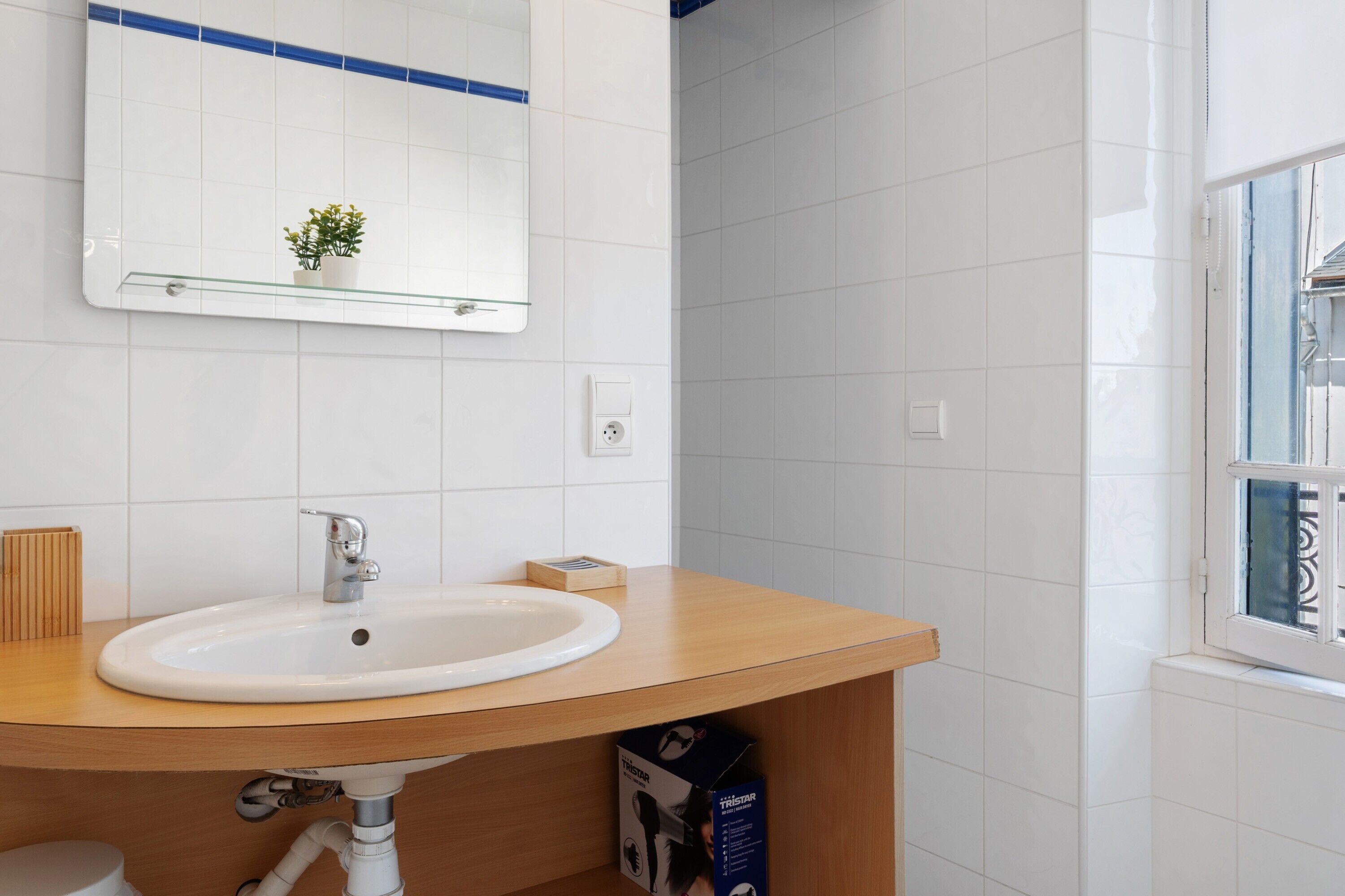 A bathroom with a white sink, mirror, and white tiles.