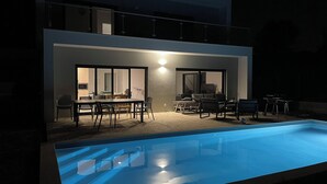 Una casa moderna con piscina, zona pranzo e soggiorno dotato di camino.