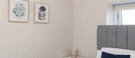 Una camera da letto con un letto, un comodino, una lampada e due quadri appesi al muro.