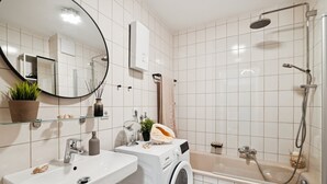 A modern bathroom with a sink, mirror, washing machine, and shower. - Luxurious apartment I Fully equipped I University within walking distance (Homburg)