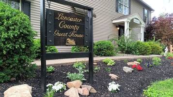 Une enseigne indiquant l’emplacement de la « Lancaster County Guest House », avec un jardin situé devant.