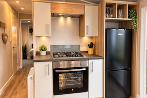 A modern kitchen with a gas stove, oven, and black refrigerator.