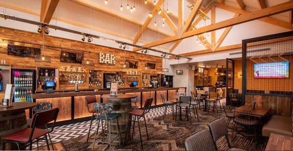 A bar area with wooden beams, bar stools, and a variety of liquor bottles.