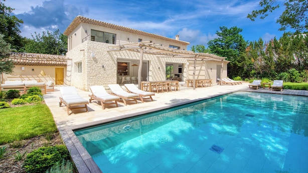 Ein zweistöckiges Haus mit Pool, Sitzgelegenheit im Freien und einer Steinfassade.
