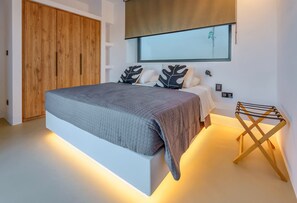 Ein modernes Schlafzimmer mit einem großen Bett, einem Holzschrank und einem ungewöhnlichen Wandspiegel.