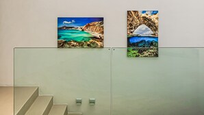 A staircase with a glass barrier and two framed photographs of coastal landscapes. - Paros Villa Skylines Estate III (Paros)