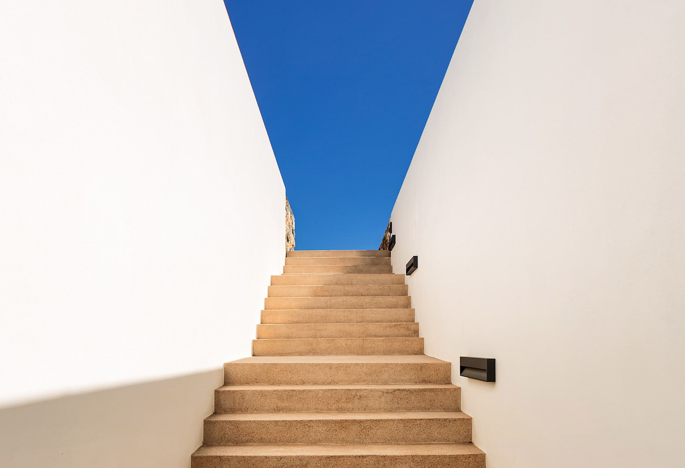 A staircase leading upwards with a clear blue sky above.