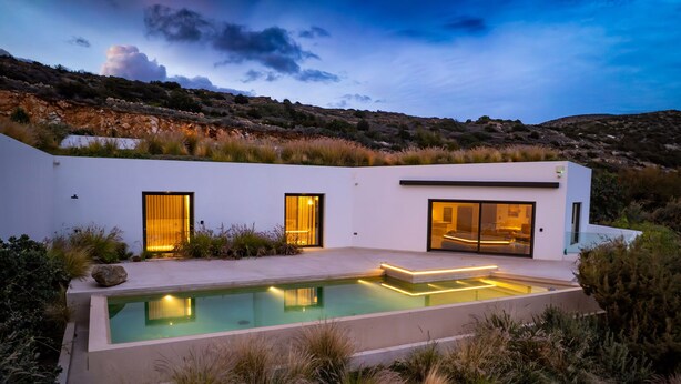 A modern house with a swimming pool, large windows, and a view of the surrounding landscape. - Paros Villa Skylines Estate III (Paros)
