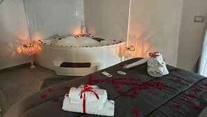 A spa room with a massage table, rose petals, candles, and a white bathtub. - B&b HOUSE NAPLES CAPODICHINO (Napoli)