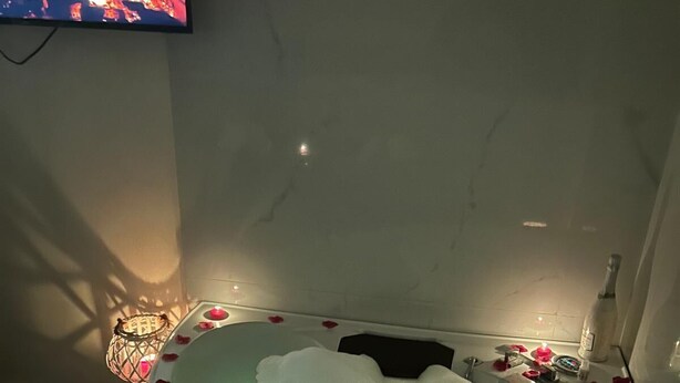 A bathtub with ice and rose petals, a bottle of alcohol, and a lit candle. - B&b HOUSE NAPLES CAPODICHINO (Napoli)