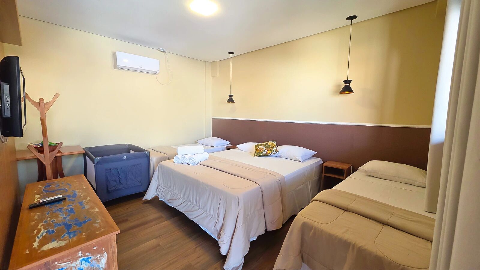 Une chambre d’hôtel avec deux lits, un bureau, une chaise, une télévision et un appareil de climatisation.
