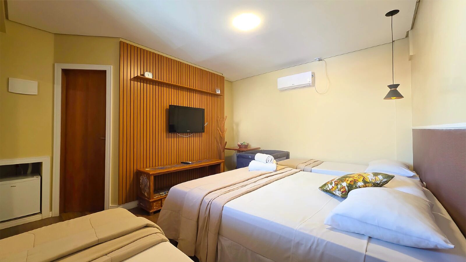 A hotel room with a bed, a television, a wardrobe, and a desk.