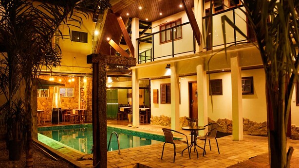 Um edifício de dois andares com piscina, área de estar ao ar livre e um muro de pedra.