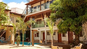 Um edifício de dois andares com piscina, área de estar ao ar livre e vegetação exuberante.
