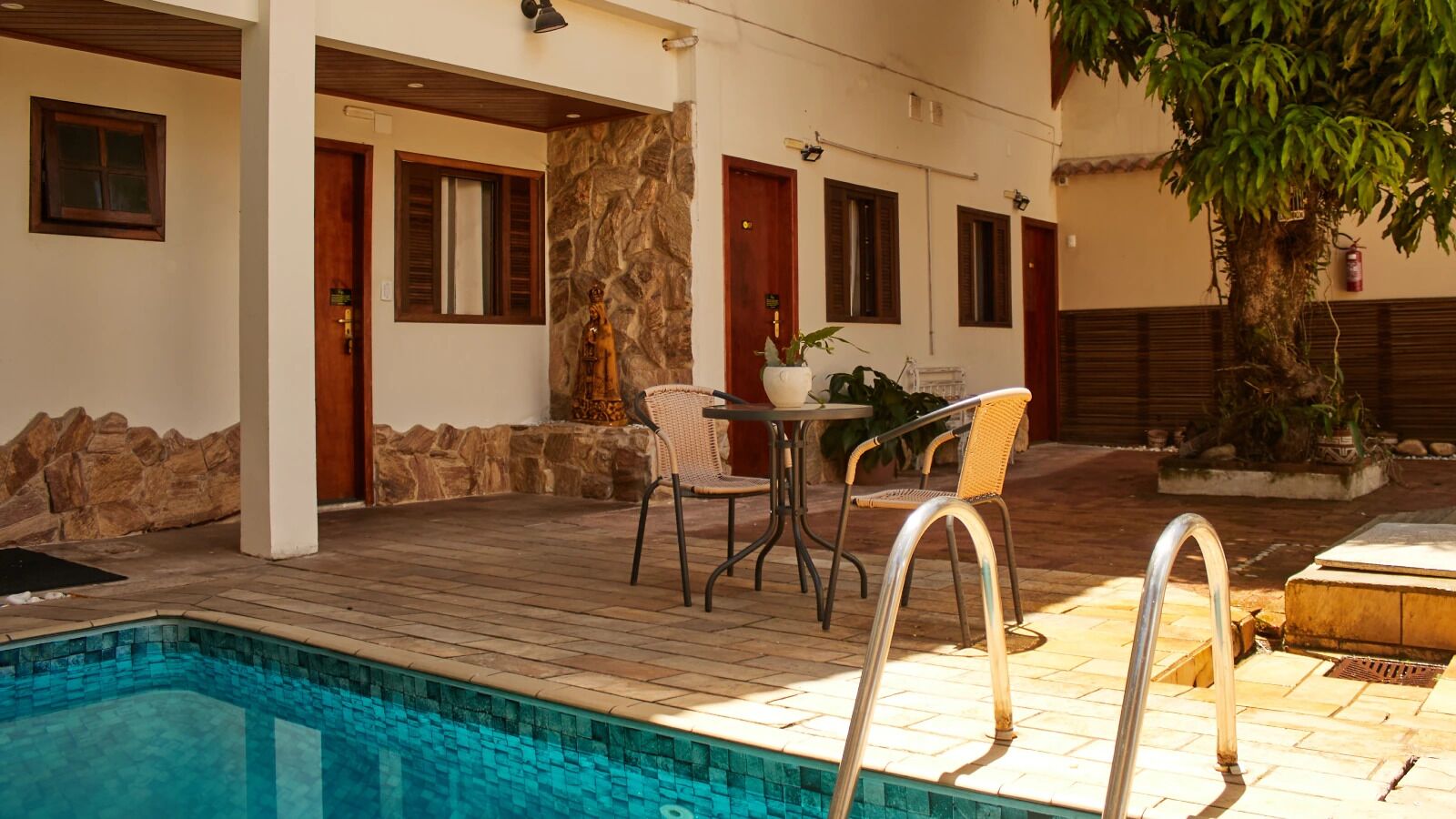Ein Poolbereich mit Tisch und Stühlen, Steinmauern und einer Holzterrasse.