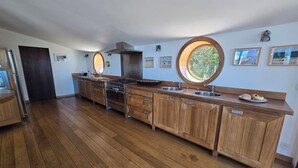 A modern kitchen with wooden cabinets, stainless steel appliances, and a large window.