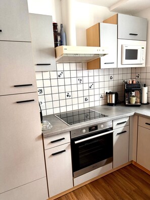 A modern kitchen with a built-in oven, microwave, and a coffee machine. - Apartment "Fewo Stembers" with Sea View, Shared Garden, and Wi-Fi (Heideck)