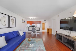 A modern living room with a blue sofa, a coffee table, and a flat-screen TV. - Brickell Bay 1720 (Miami)