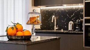 A kitchen counter with a bowl of oranges and a glass dome displaying croissants. - BDC - LuxuryLifeStyle (Roma)