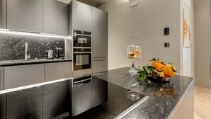 A modern kitchen with a marble countertop, stainless steel appliances, and a fruit bowl. - BDC - LuxuryLifeStyle (Roma)