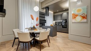 A modern kitchen with a central island, a dining area with a round table and chairs, and a pendant light. - BDC - LuxuryLifeStyle (Roma)